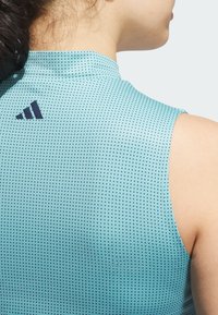 Bezrękawnik sportowy w jasnoniebieskim kolorze, z teksturowanym wzorem małych kropek i czarnym logo na plecach. Miękki, przylegający krój.