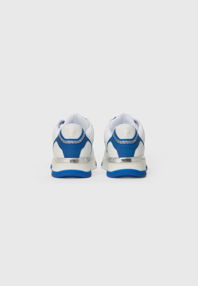 Baskets de sport blanches avec des accents bleus, des détails en argent et un logo sur le talon. Matériaux en mesh et synthétiques avec une semelle rembourrée.