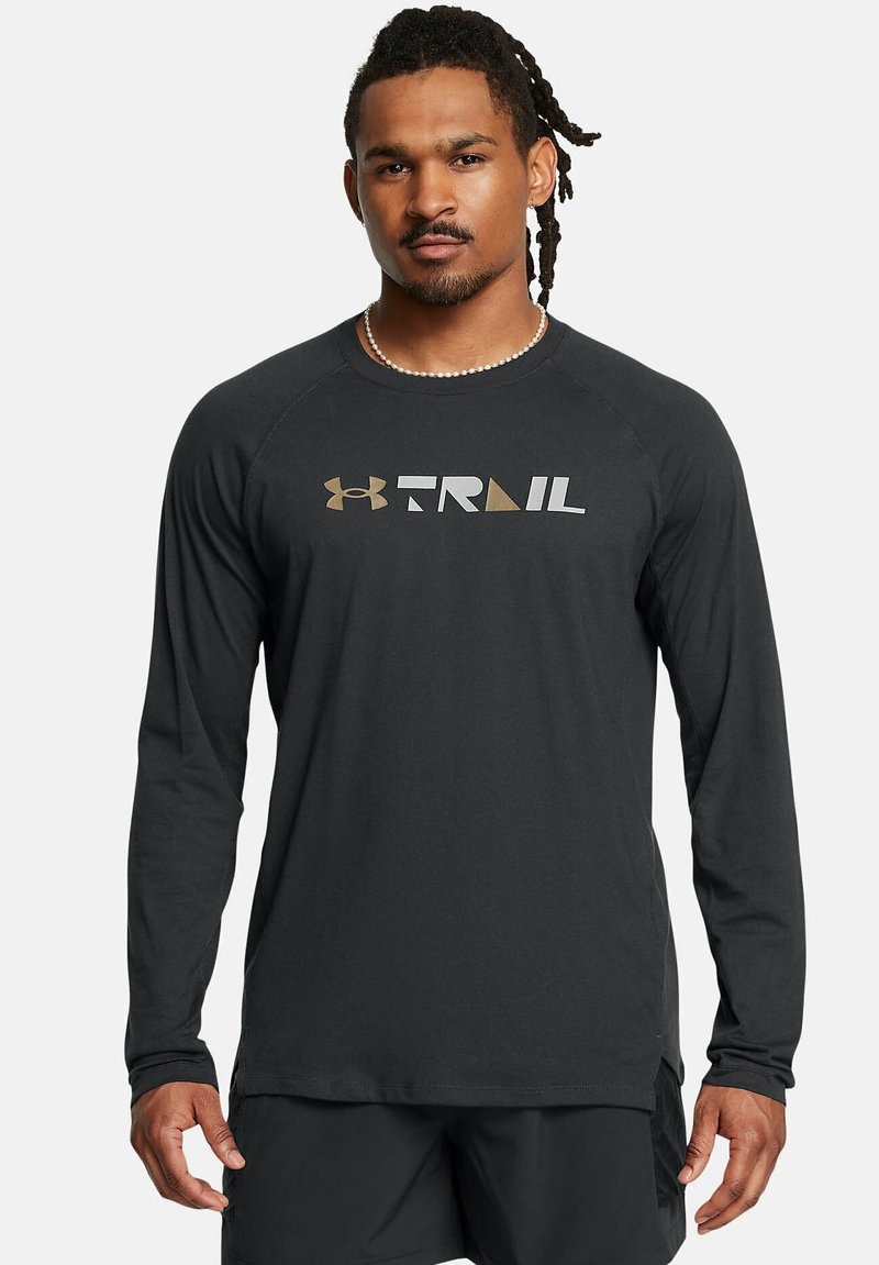 Langærmet sort skjorte lavet af blødt stof med "TRAIL" logo i grå og guld, med rund halsudskæring og raglanærmer.