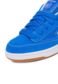 Blaue Wildleder-Sneaker mit strukturierter Oberseite, weißen Nähten und Gummisohle. Verfügt über dicke Schnürsenkel und ein markenbesticktes Zungenetikett.