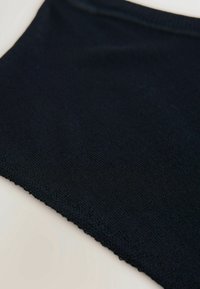 Zwart gebreide stof met een gestructureerde afwerking, omrand met een delicate, opengehaakte patroon. Zacht en flexibel materiaal.