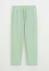 Pantalons de survêtement vert clair en tissu texturé, avec une taille élastique, un cordon de serrage et des ourlets côtelés. Présente des rayures verticales.