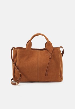Sac à main en suède marron avec des poignées courtes et une longue bandoulière réglable sur un fond clair.
