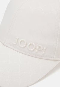 Bela kapa z embosiranim vzorcem, z vezenim logotipom "JOOP!" na sprednji strani. Material je gladek, z strukturirano zasnovo in ukrivljenim vizirjem.
