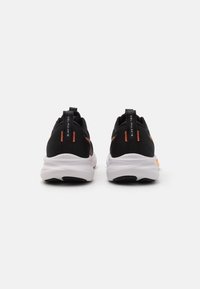 Zapatillas deportivas negras con empeine texturizado, detalles naranjas y suelas blancas. Presentan etiquetado de marca en la parte trasera y un diseño elegante y de perfil bajo.