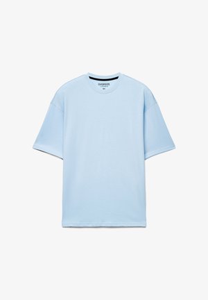 Maglietta oversize azzurro chiaro in cotone, con scollo tondo e maniche corte, dalla texture semplice e liscia senza motivi.