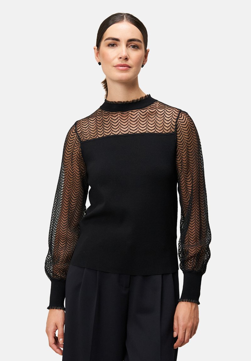 Schwarzer Pullover mit semitransparenten, strukturierten Spitzenärmeln im Fischgrätmuster und einem hohen Halsausschnitt mit rüschigem Rand.