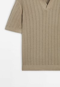 Pull en maille beige à manches courtes avec col en V, motif côtelé vertical texturé, poignets et ourlet ajustés.