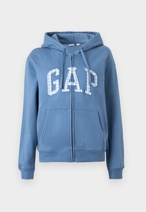 Blauwe zip-up hoodie van een katoenmix, met een kangoeroezak en een groot "GAP" logo op de voorkant in witte en blauwe patronen.