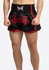 Sorte satinshorts med røde detaljer og "TAPOUT"-logo i fed, stiliseret skrift. Elastisk livrem for komfort og fleksibilitet.