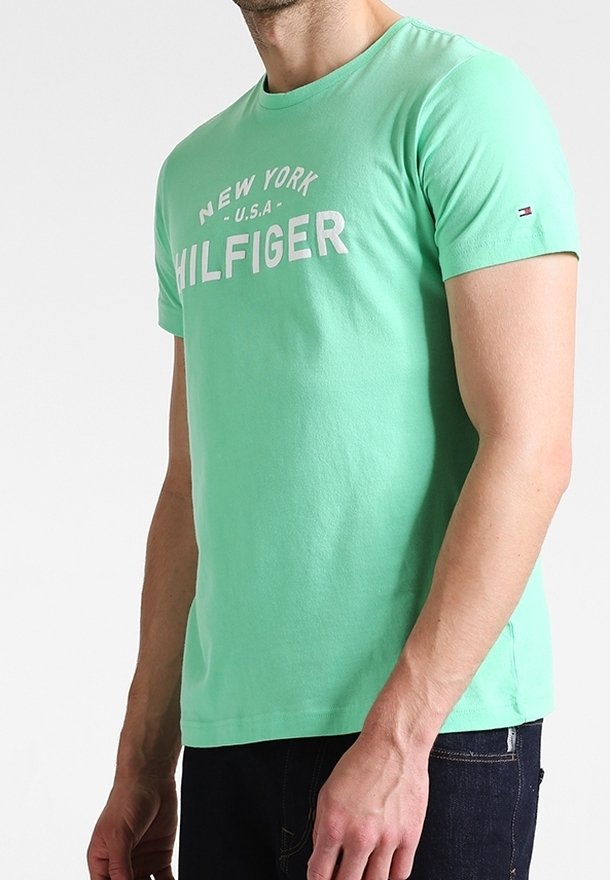 Tyrkysové bavlněné tričko s krátkým rukávem, zdobené výrazným bílým nápisem "NEW YORK U.S.A. HILFIGER" a malým logem na rukávu.