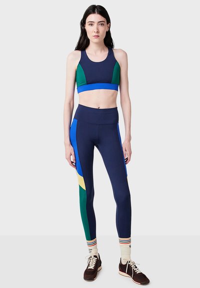 Marinsvart atletisk crop top med gröna och blå paneler, kombinerad med högmidjade marinsvarta leggings med blå, gröna och gula detaljer.