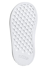 Biela podrážka tenisky s hexagonálnym textúrovým vzorom, s hladkým okrajom a embosovaným logom na spodnej strane. Ľahký gumový materiál.