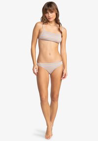 Prúžkovaný bikiny set s bandeau topom a nízko strihanými nohavičkami. Farby zahŕňajú svetlomodrú, ružovú a žltú. Tkanina má hladkú textúru.
