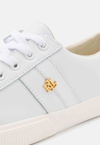 White leather sneaker with white laces, gold "RL" logo on side, detailed stitching, and textured white rubber sole.