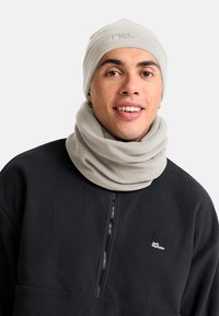 Un bonnet en polaire gris clair et une écharpe de cou portés avec un pull en polaire noir, comportant un patch de marque sur le pull.