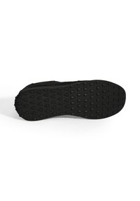 Semelle de chaussure de sport noire avec un dessous en caoutchouc texturé, présentant de petits motifs triangulaires pour une meilleure adhérence et traction.