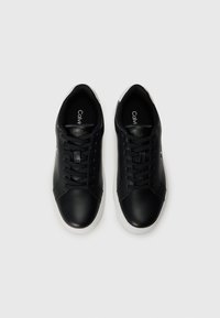 Zwarte leren sneakers met een gladde textuur, ronde neus, witte rubberen zool en veters. Voorzien van een subtiele logo op de tong. Bovenaanzicht.