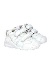 Zapatillas blancas de cuero con suela de goma, que cuentan con dos correas ajustables de velcro y un logo plateado en el lateral. Diseño de punta redondeada.