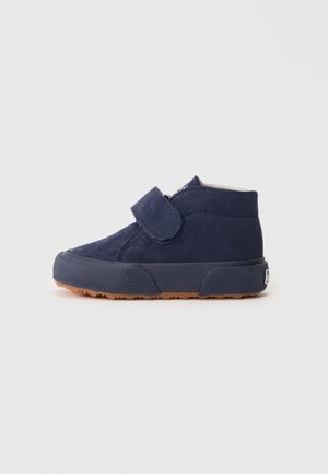 Scarpa alta in suede blu navy con strap in Velcro, suola in gomma testurizzata e cavigliera imbottita. Presenta una punta rotonda e una suola in gomma a contrasto.
