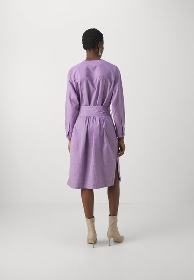Purple striped shirt dress with long sleeves, a tied waist, and a split hem, made from lightweight fabric. Features buttons and a structured fit.