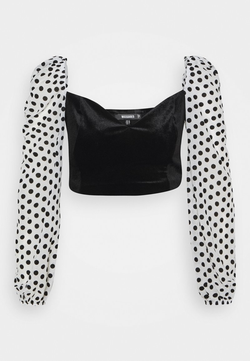 Top court noir avec manches longues blanches à pois noirs, poignets élastiques, encolure carrée et épaules froncées.
