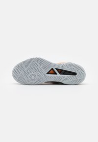 Semelle de sneaker grise avec des motifs de tread en zigzag et circulaires élaborés, présentant des accents triangulaires noirs et oranges dans la zone médiane.