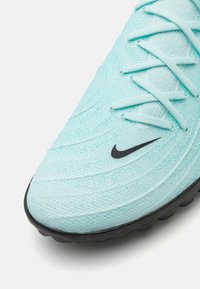 Baskets de sport bleu clair avec un dessus texturé, fermeture à lacets et un logo Swoosh Nike noir. Présente une semelle en caoutchouc avec traction.