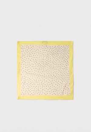 Kvadratisk beige tørklæde med små sorte polkaprikker og en klar gul kant, lagt fladt på en hvid overflade.