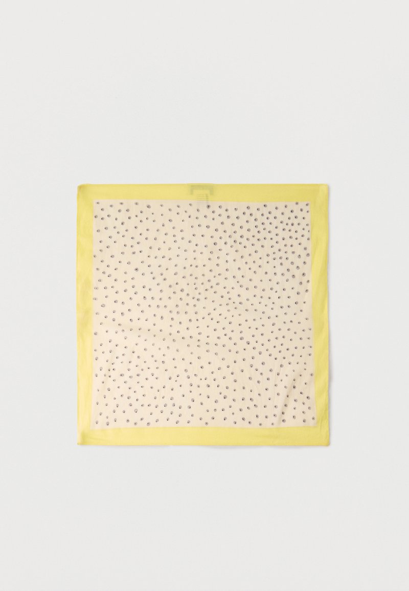 Τετράγωνο μπεζ μαντήλι με μικρές μαύρες πουά και λαμπερό κίτρινο περίγραμμα τοποθετημένο επίπεδα σε λευκή επιφάνεια.