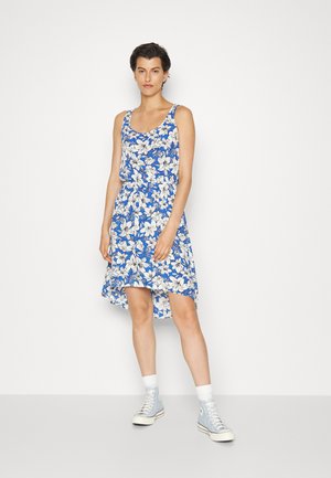 Vestido de tanque floral em azul e branco com uma bainha assimétrica. Combinado com ténis de cano alto azul claro e meias brancas até ao tornozelo.