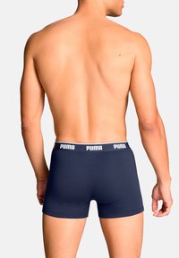 Marineblaue Boxershorts mit einem grauen, gebrandeten Bund, figurbetonter Passform und glattem, dehnbarem Stoff, von hinten betrachtet.