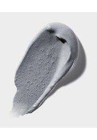 Graue Creme mit einer glatten, glänzenden Textur und feinen Blasen, geformt wie ein geschwungener Strich auf einem weißen Hintergrund.