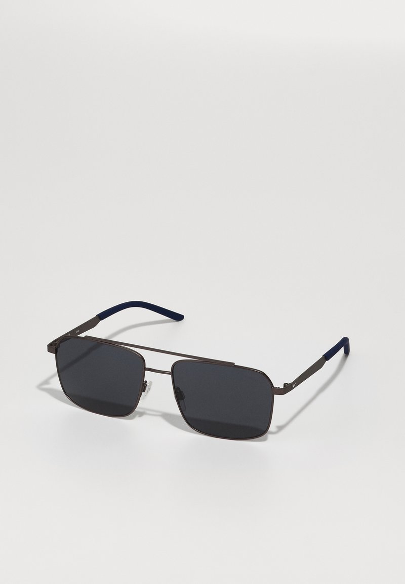 Gafas de sol rectangulares con lentes oscuros, marco metálico delgado en color marrón y puntas de patilla acentuadas en azul. Diseño ligero, con un hardware mínimo.