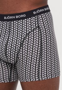 Fekete és szürke mintás boxer alsó, logós derékkal, geometrikus mintával és kontrasztos varrási részletekkel.
