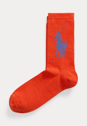 Calza arancione brillante con un giocatore di polo blu a cavallo che tiene un mazzolino sollevato, design sulla parte del polpaccio.