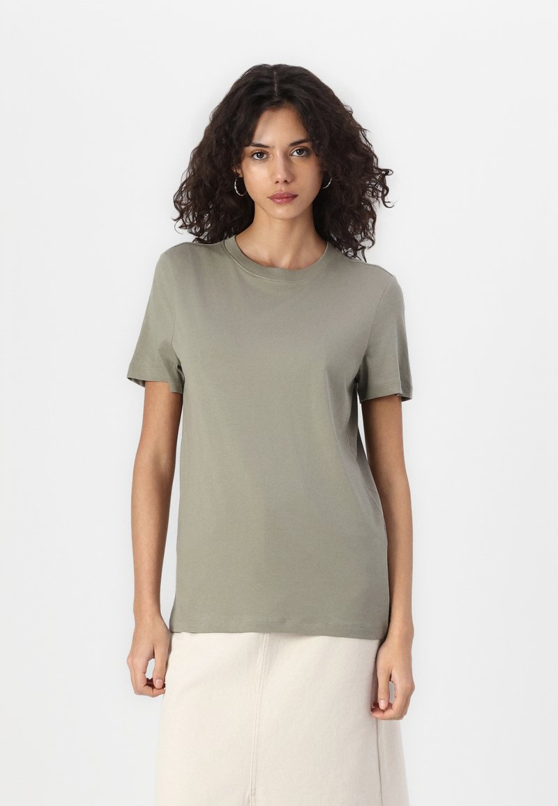 Olive green cotton t-shirt with a crew neckline and short sleeves, featuring a relaxed fit and smooth texture. Worn with a cream-colored skirt.