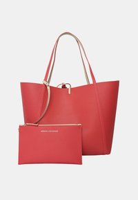 Borsa tote in pelle rossa con accenti beige e manici lunghi, accompagnata da un sacchetto con zip coordinato caratterizzato dal logo "Armani Exchange".