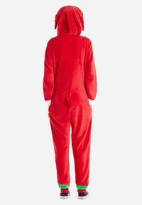 Red fleece onesie with a hood, featuring floppy ears, a tail, and green accents at the cuffs. Soft texture, full back view.