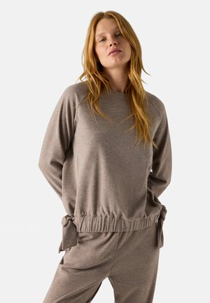 Sudadera de color marrón claro hecha de una tela suave, con un cuello redondo, mangas largas y detalles recogidos con lazos en la cintura.