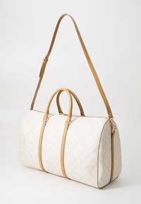 Witte geruite canvas sporttas met tan lederen accenten, dubbele handgrepen aan de bovenkant en een afneembare schouderband, voorzien van een ritssluiting.