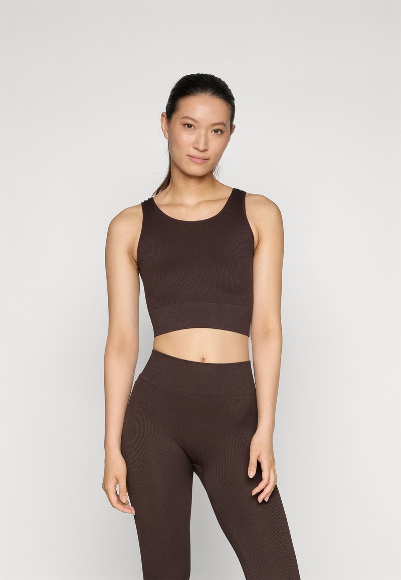Smešani smeđi rebrasti crop top u kombinaciji s usklađenim tajicama visokog struka. Tkanina ima glatku teksturu i kroj koji ističe siluetu.