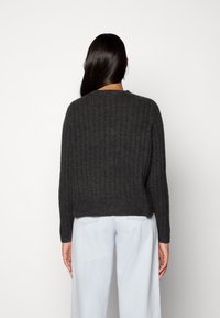 Maglione lavorato a maglia grigio scuro con texture a coste, design cropped e maniche lunghe. Presenta un collo rotondo e dettagli sottili sulla parte posteriore.