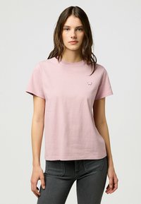 Lyserød t-shirt med korte ærmer lavet af bomuld, med rund halsudskæring og et lille broderet logo på venstre bryst.