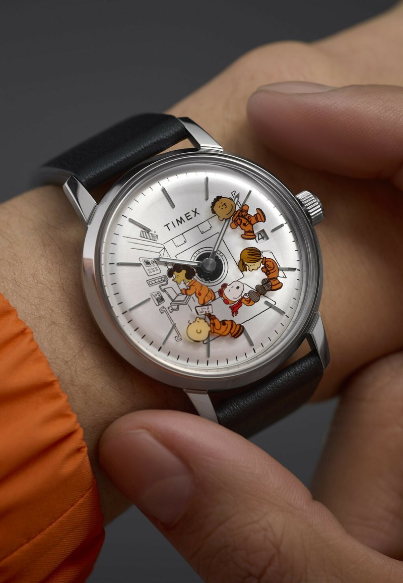 Srebrny analogowy zegarek z czarnym skórzanym paskiem, z cyframi w formie postaci z kreskówek na tarczy, łączący w sobie zabawny design i prostotę.