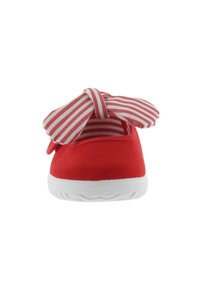 Zapato infantil de lona roja con suela blanca, con un gran lazo de tela a rayas rojas y blancas en la parte superior.