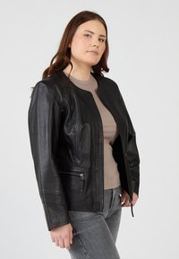 Schwarze Lederjacke mit rundem Ausschnitt, Frontreißverschluss und seitlichen Reißverschlusstaschen. Die Jacke hat eine glatte Textur und eine maßgeschneiderte Passform.