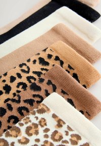 Set van zeven sokken met effen kleuren in zwart, crème en verschillende tinten bruin, met twee leopardprintpatronen. Zachte textuur.