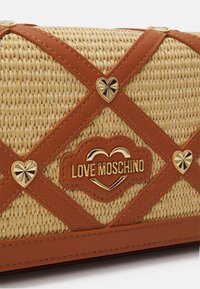 Fonott szalma kézi táska barna bőr kiegészítőkkel, arany "Love Moschino" logóval és szív alakú díszítésekkel. Texturált és strukturált kialakítás.