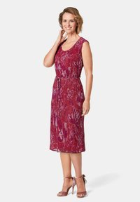 Ärmelloses, knielanges Kleid mit einem lebhaften Muster aus roten und lila Blumen, aus einem strukturierten Stoff und mit einem passenden Gürtel in der Taille.